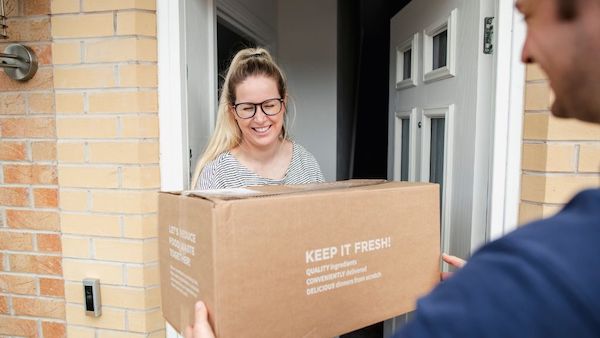 Courier delivering a parcel to a woman with smiling face