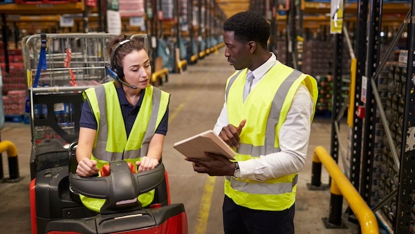 Two warehouse workers looking at a document